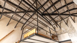 Une pièce avec des poutres apparentes et un espace aménagé en mezzanine.