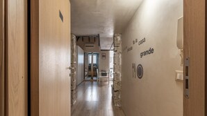 Un couloir doté d’un plancher en bois, d’un mur en pierre orné d’inscriptions et d’une porte donnant sur une autre pièce.