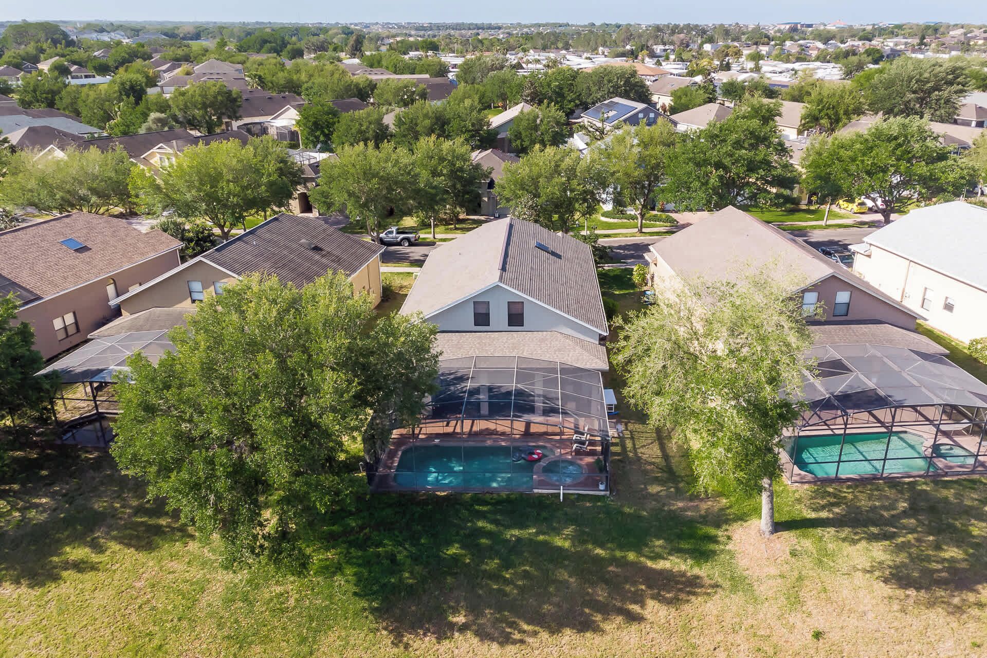 A residential area with houses, trees, and a swimming pool.