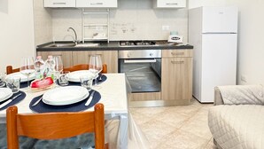 A compact kitchen with white cabinets, a built-in oven, and a refrigerator. - Casa Vacanza Brezza Marina - Marine Pearl (Chioggia)
