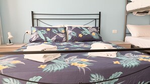 A bed with floral bedding, a bedside table with a lamp, and a bunk bed to the right. - Casa Vacanza Brezza Marina - Marine Pearl (Chioggia)