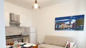 A compact living space with a kitchenette, dining area, and a sofa. - Brezza Marina - Sea Breeze by Ca-sa Check (Chioggia)