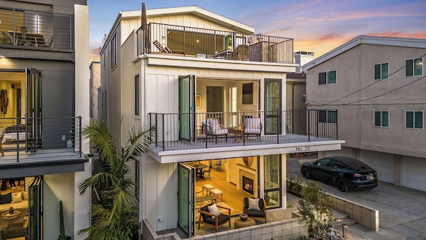 A modern two-story residential building with a balcony, a fireplace, and a car parked in the driveway. - Beach Paradise Stunning 3-story in Long Beach! (Long Beach)