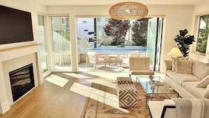 A modern living room with a fireplace, a sofa, a coffee table, and a patterned rug. - Beach Paradise Stunning 3-story in Long Beach! (Long Beach)