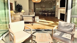 A modern living room with a sofa, chairs, a coffee table, and a dining area with a chandelier. - Beach Paradise Stunning 3-story in Long Beach! (Long Beach)