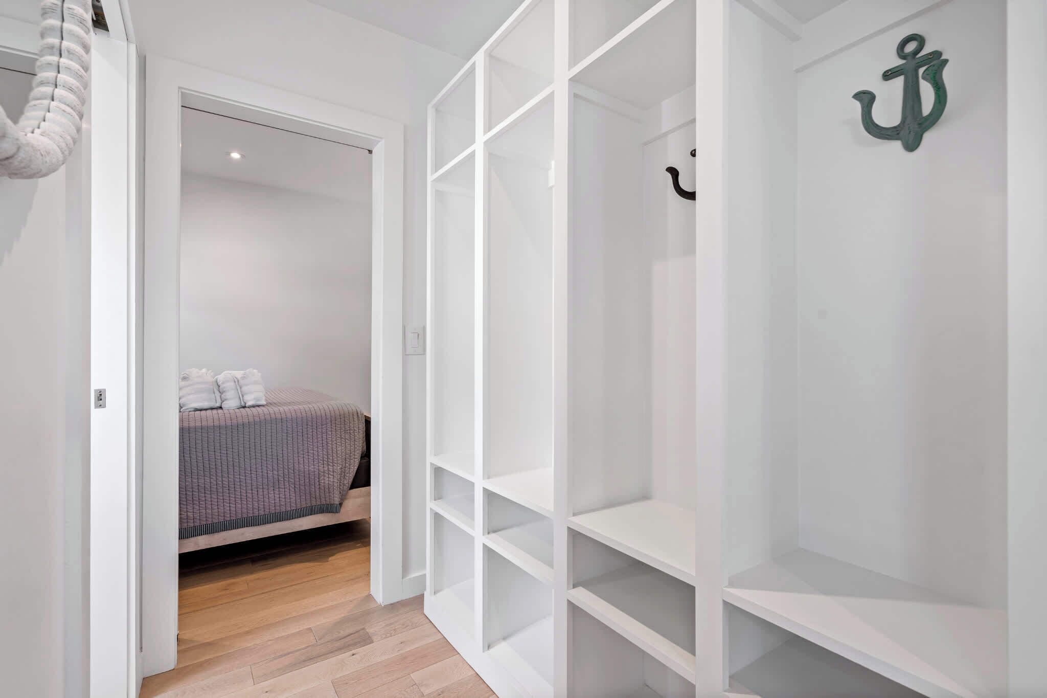 A bedroom with a bed, a white wardrobe, and a small shelf.