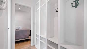 A bedroom with a bed, a white wardrobe, and a small shelf.