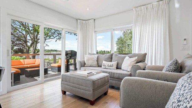 A spacious living room with a grey sofa set, a grey ottoman, and a large sliding glass door leading to an outdoor patio. - Latitude Adjustment Walk to Beach & Dining! (Scarborough)