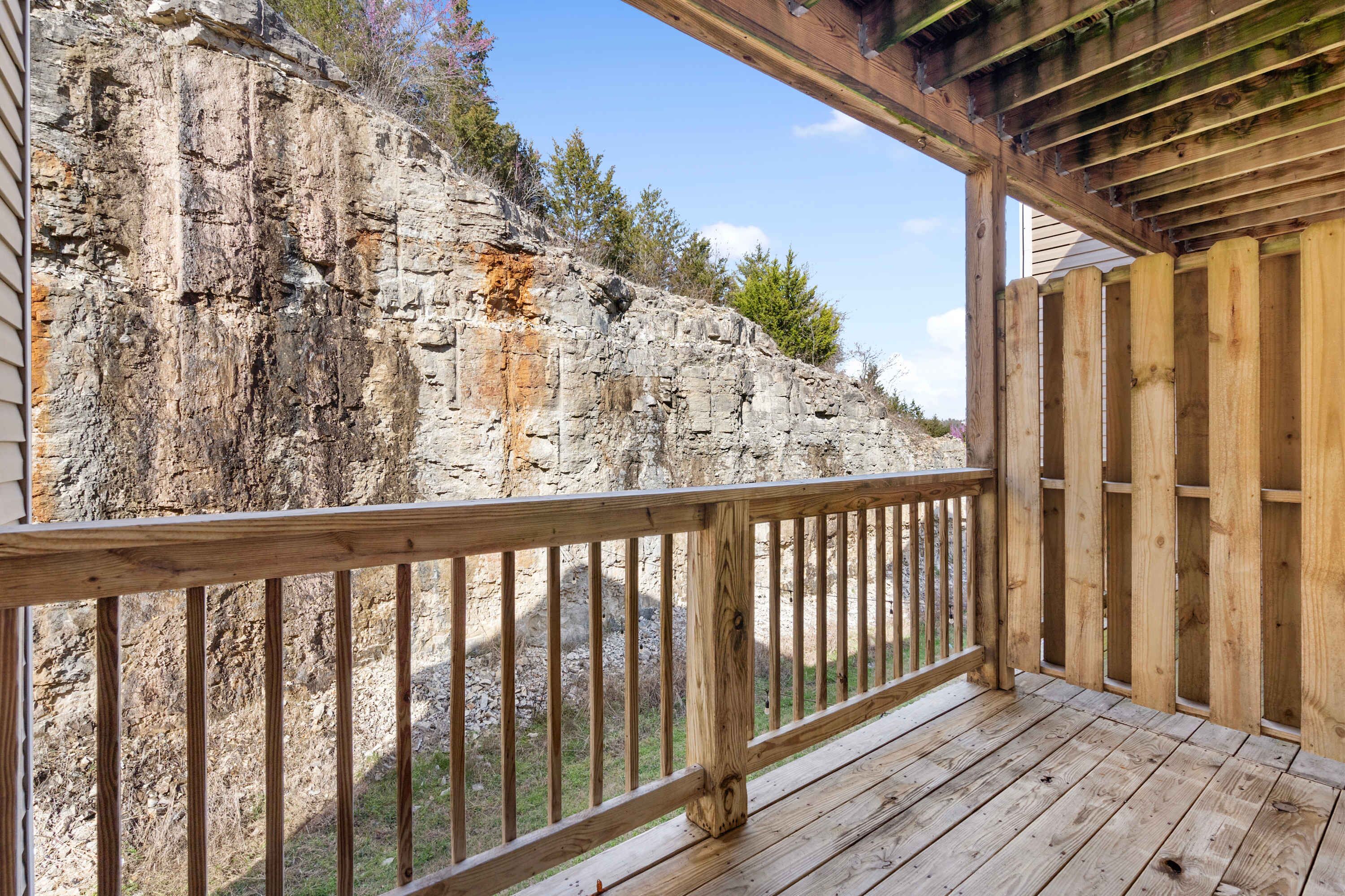 A wooden deck with a railing overlooking a rocky cliff.