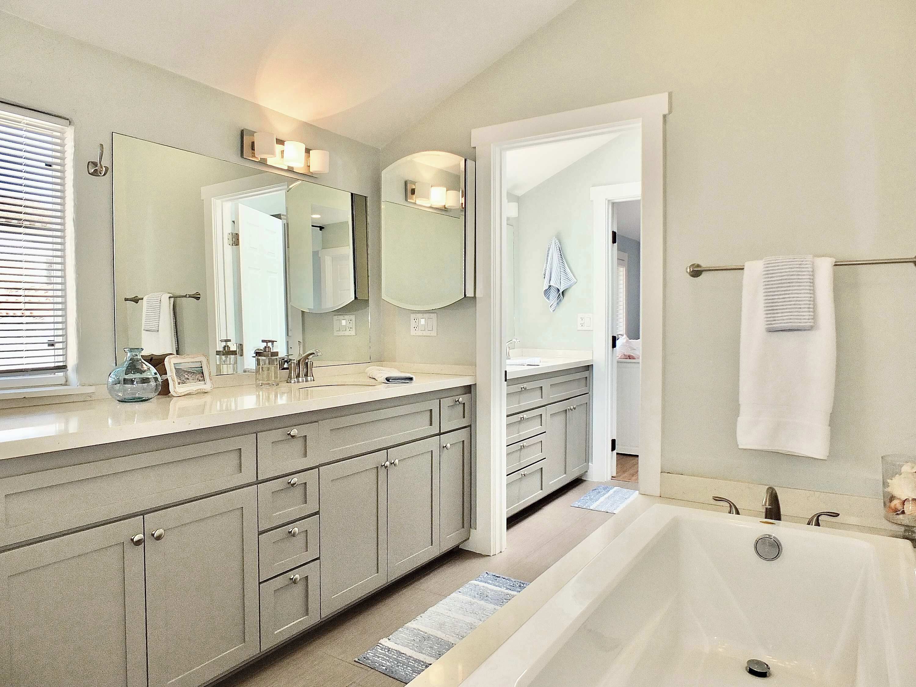 A modern bathroom with a large bathtub, double vanity with a mirror, and a walk-in shower.