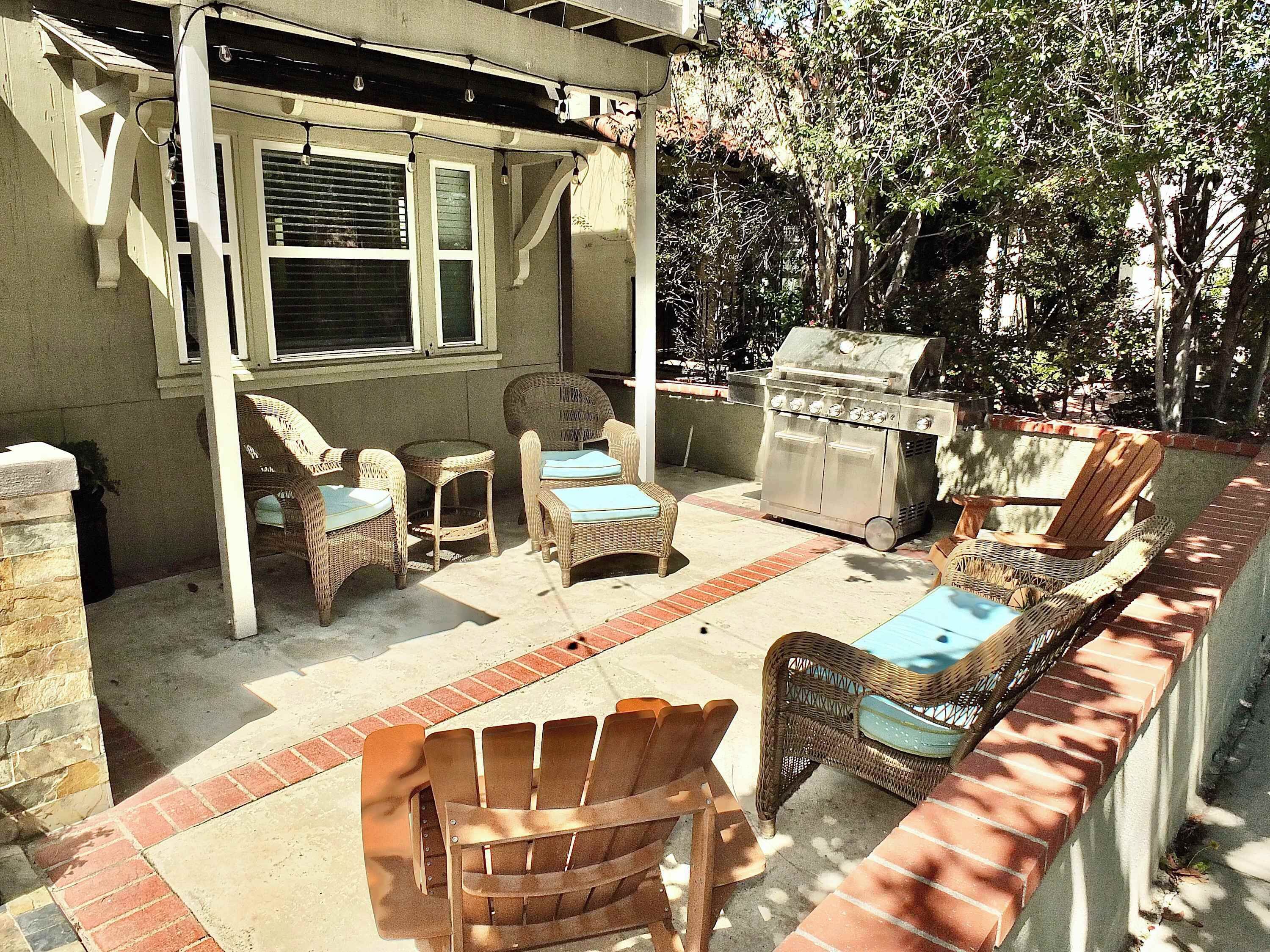An outdoor patio with wicker furniture, a grill, and a covered seating area.