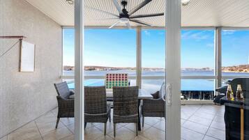 A balcony with wicker chairs, a table, and a view of the sea.