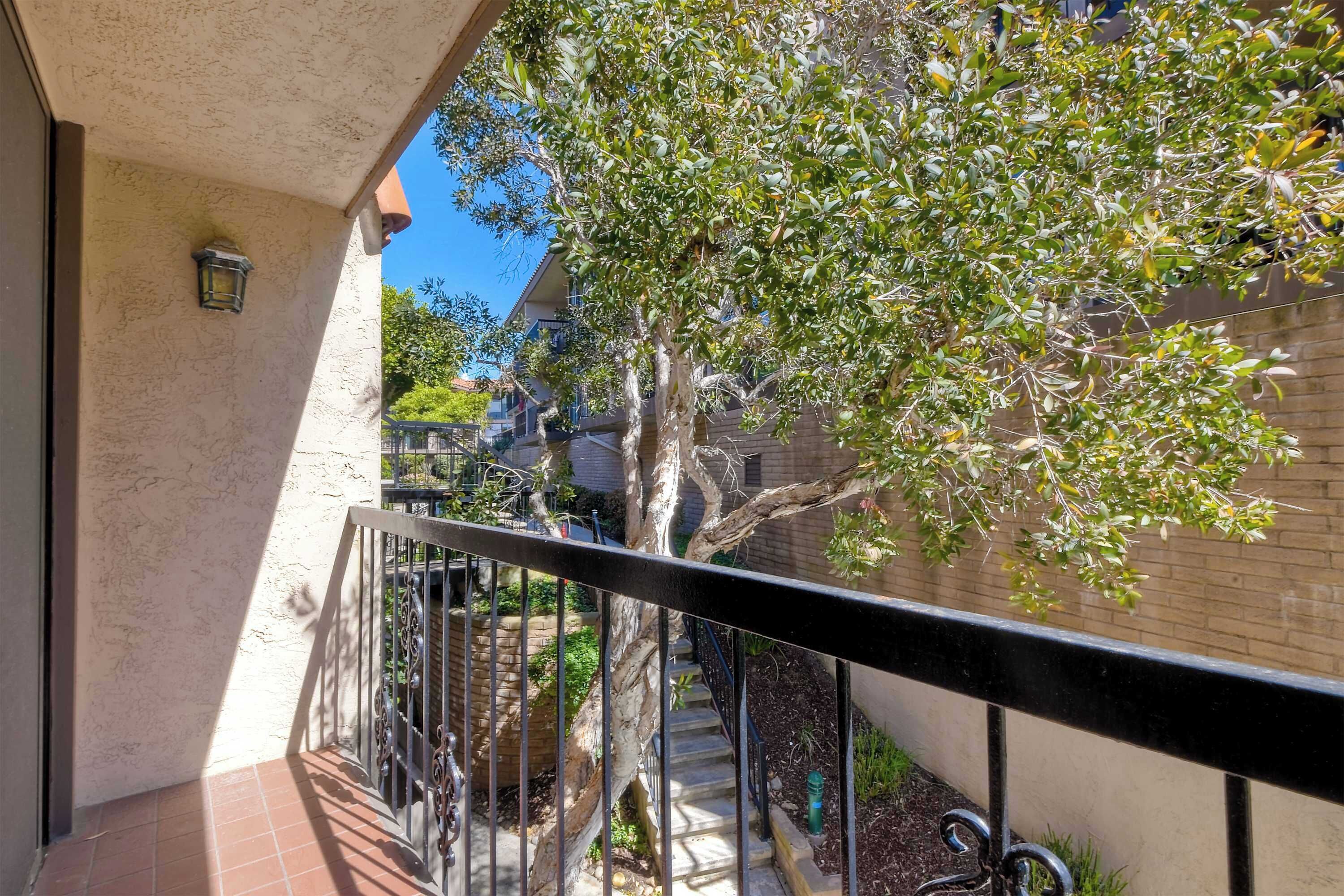 Un balcón con vista a un árbol y una escalera que lleva a un edificio.