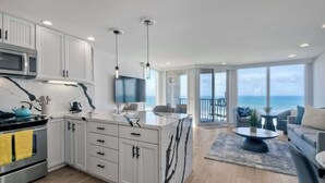 Una cucina moderna con mobili bianchi, un'isola centrale e vista sull'oceano.