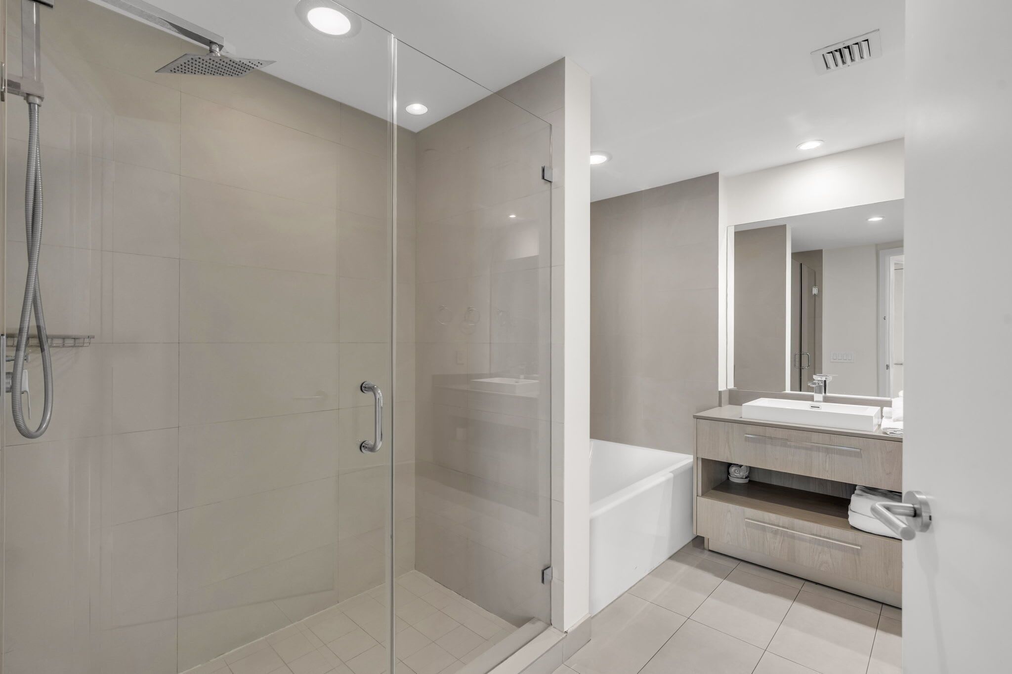 A modern bathroom with a glass-enclosed shower, a white sink, and a mirror above the vanity.