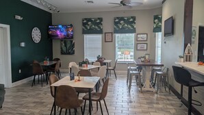Ein Restaurant mit mehreren Tischen und Stühlen, einem Deckenventilator und einem Fernseher an der Wand.