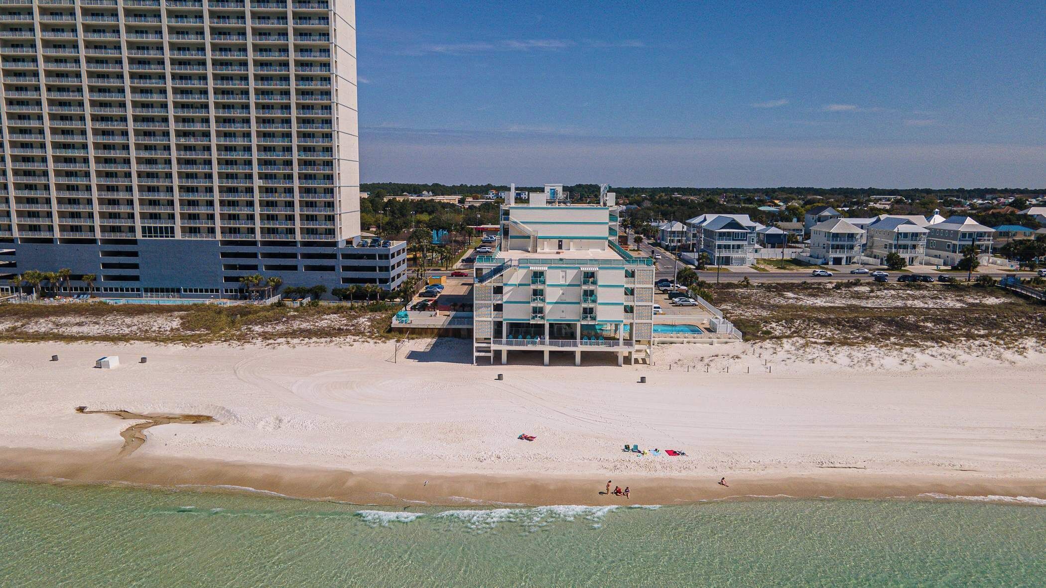 Un hotel frente al mar con varios pisos, piscina y acceso directo a la playa.
