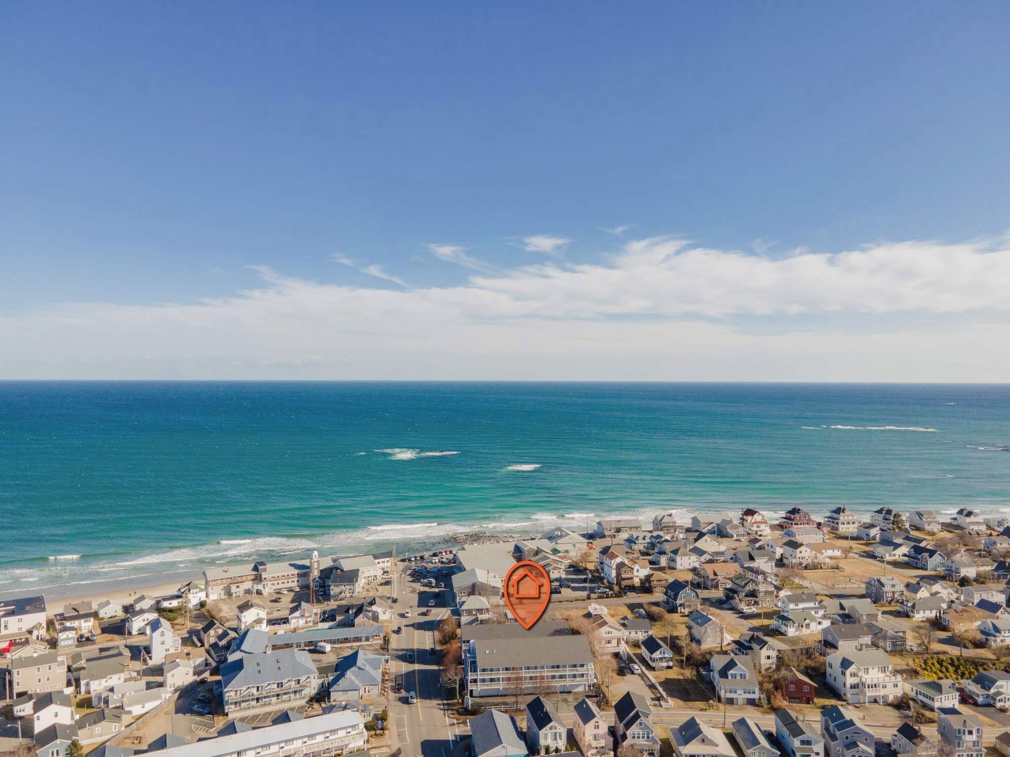An aerial view of a coastal residential area with houses, a beach, and the ocean.