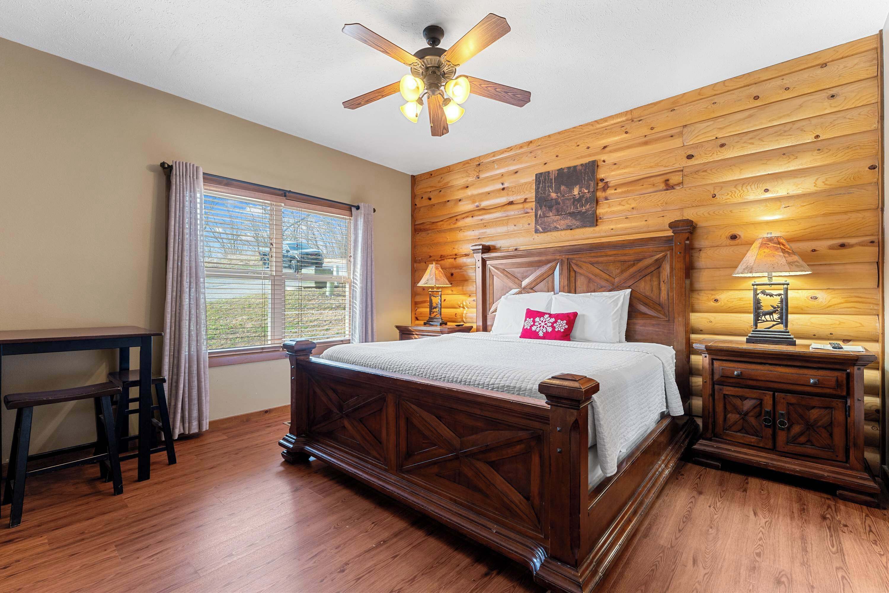 Une chambre à coucher avec un lit en bois, un bureau et un ventilateur de plafond.