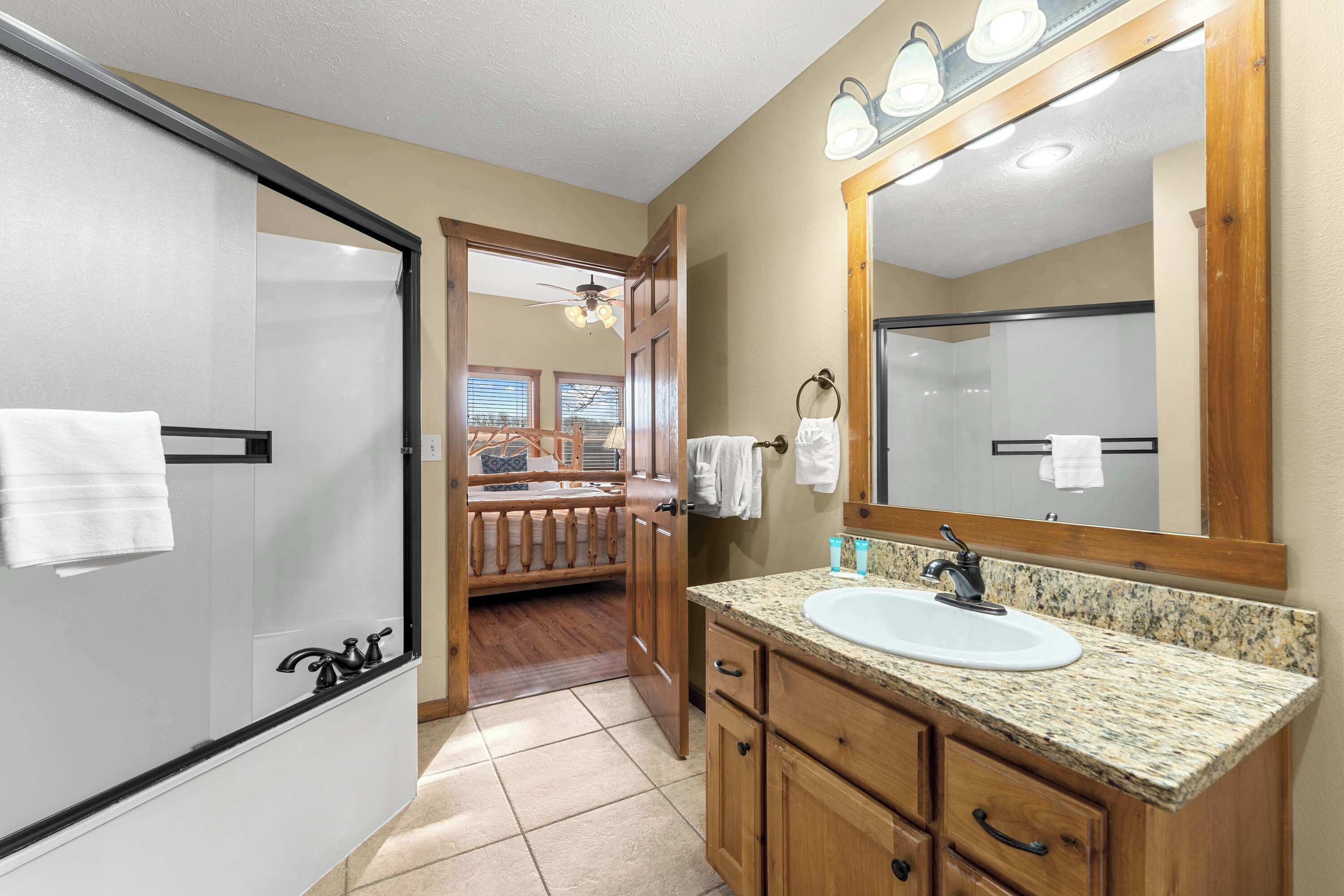 A bathroom with a white sink, wooden vanity, and a large mirror.