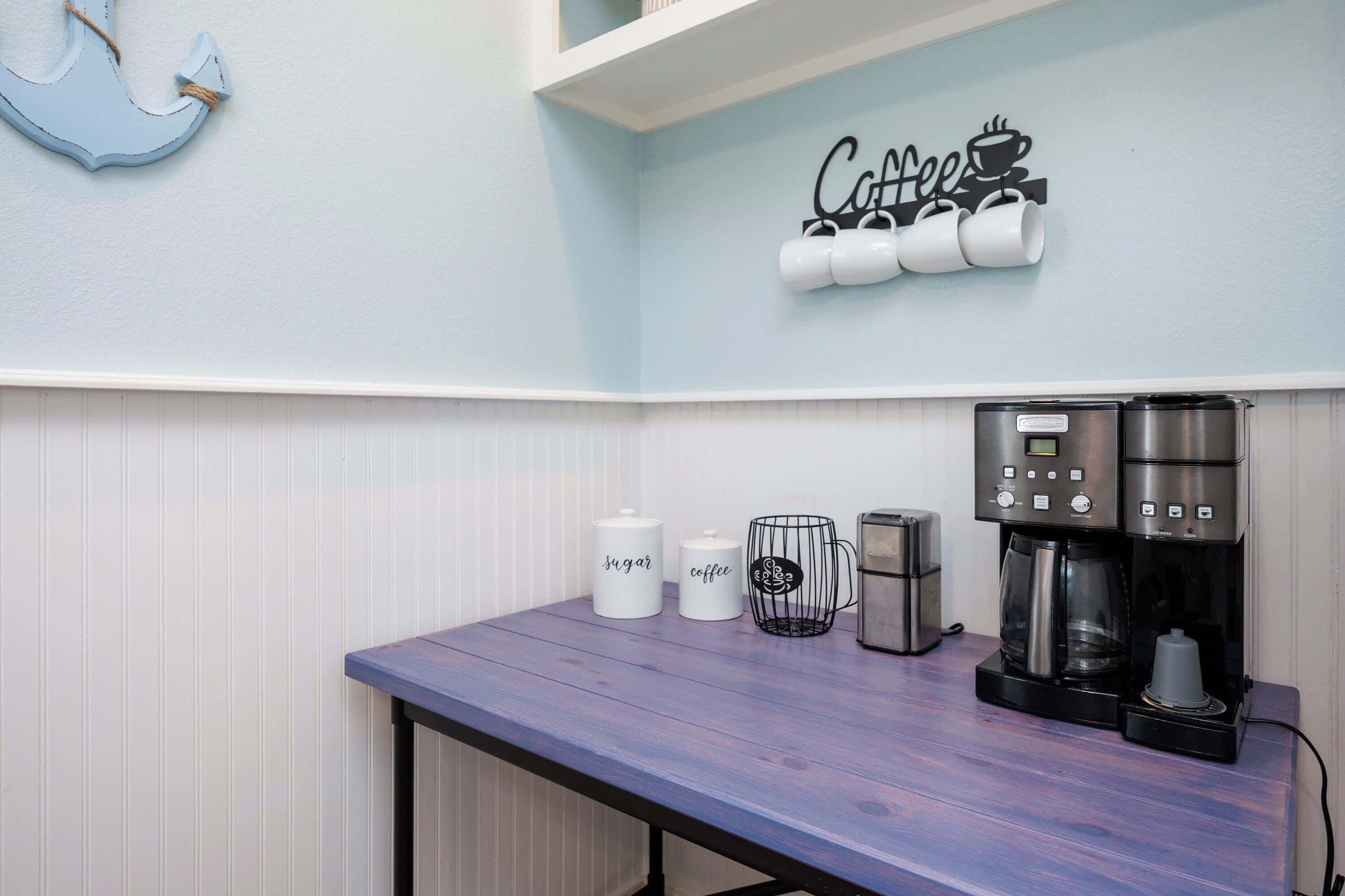 A kitchenette with a coffee station, a sugar container, a coffee mug, a toaster, and a coffee maker.