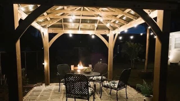 An outdoor patio with a wooden pergola, stone flooring, and a table with chairs. - Sunny Side Up A Charming Retreat! (Tampa)