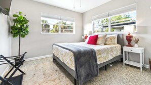 A bedroom with a bed, a nightstand, a lamp, a plant, and a ceiling fan. - Sunny Side Up A Charming Retreat! (Tampa)