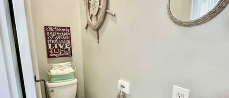 Ein Badezimmer mit Toilette, Waschbecken, Spiegel und einem motivierenden Zitat an der Wand.