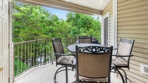 A covered patio with a table and chairs, overlooking a lush green landscape. - Lake Hideaway Waterfront Condo w/ Resort Perks! (Kimberling City)