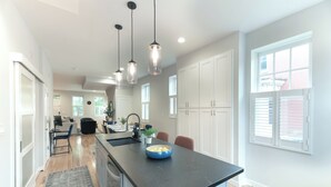 A modern kitchen with a black countertop, white cabinets, and pendant lighting. - Upscale Old Town Alexandria Retreat - Walk to King St Metro (Alexandria)