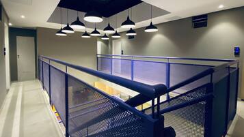 A modern interior with a mezzanine level, metal railings, and pendant lighting.