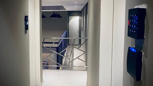 A hallway with a staircase, a door, and a wall-mounted control panel. - Sun Smart Hotel (Recife)