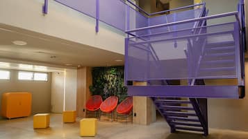 A modern interior with a purple metal staircase, orange seating, and a green wall.
