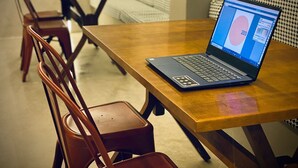A laptop on a wooden table with a chair in the foreground. - Sun Smart Hotel (Recife)