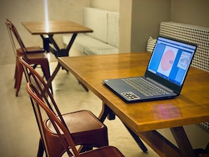 A laptop on a wooden table with a chair in the foreground.