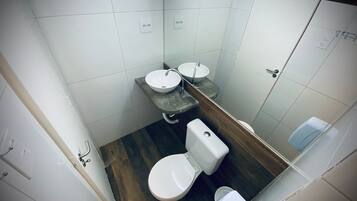 A bathroom with a toilet, two sinks, and a mirror.