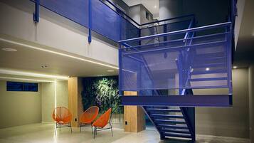 Interior moderno com escada, área de estar e parede decorada com instalação de plantas verdes.