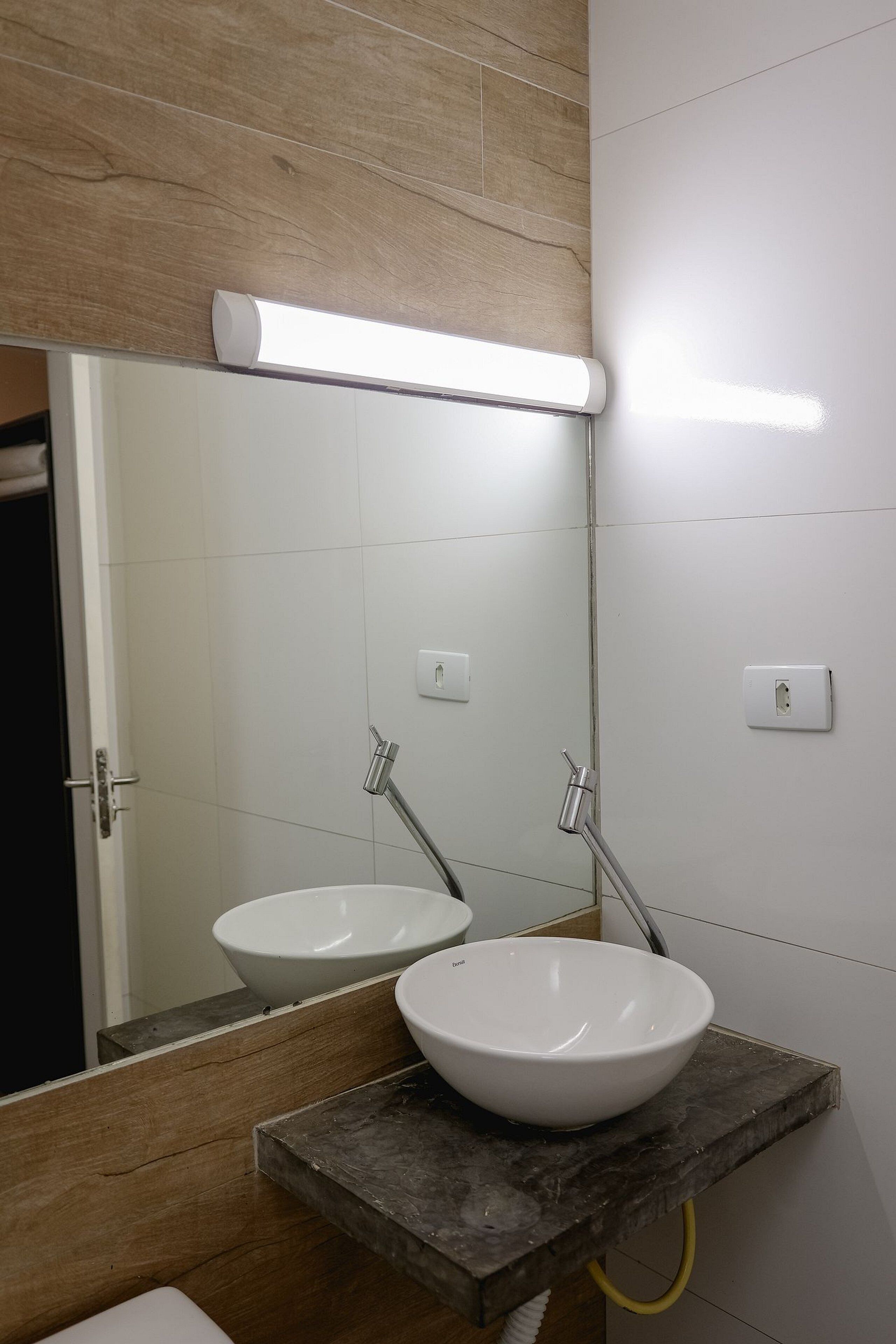 A bathroom with a white sink, a mirror, and a light fixture above the mirror.