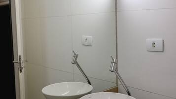 A bathroom with a white sink, a mirror, and a light fixture above the mirror.