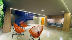 A modern interior with a staircase, orange chairs, and a checkered sofa. - Sun Smart Hotel (Recife)
