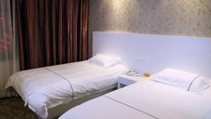 A hotel room with two single beds, a bedside table with a phone, and a curtain. - Hengdian Kaiman Hotel (Dongyang)