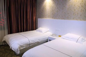 Habitación de hotel con dos camas individuales, una mesita de noche con teléfono y una cortina.