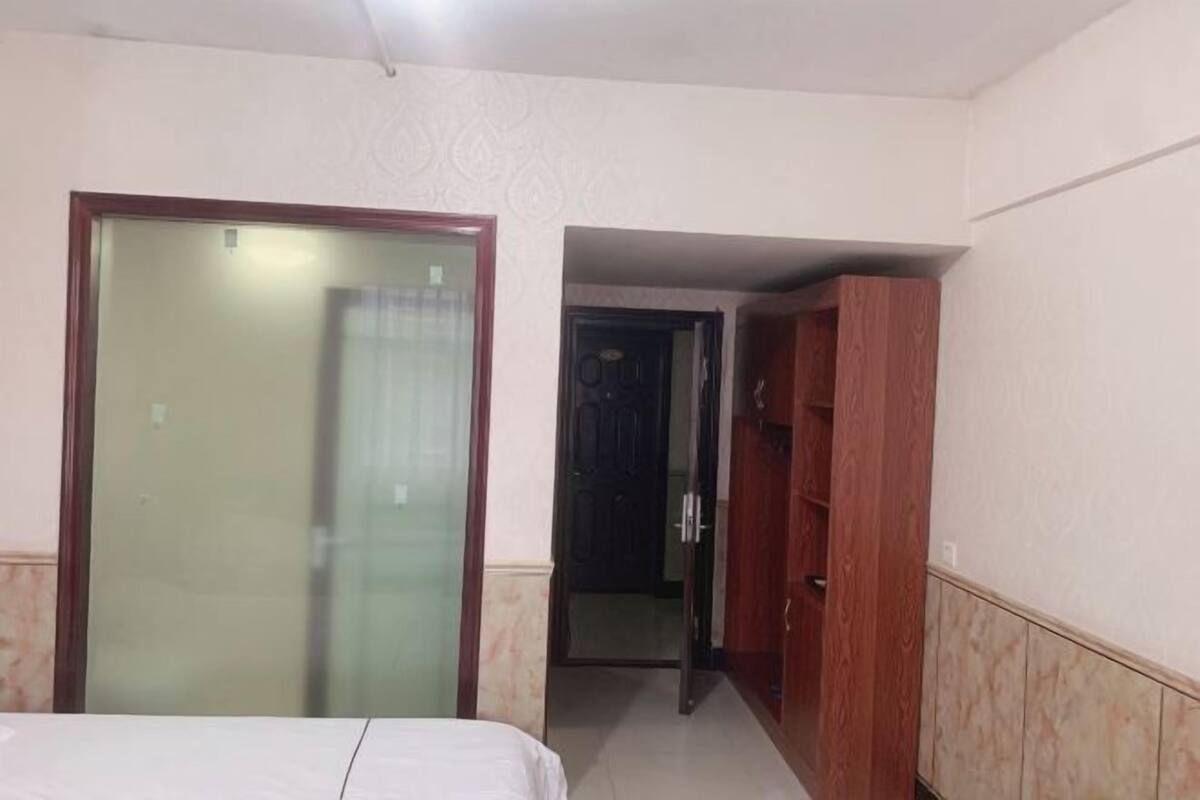 Une chambre d’hôtel comprenant un lit, une armoire et une porte donnant sur une autre pièce.