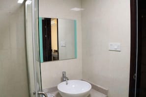 A bathroom with a glass shower enclosure, a white sink, and a mirror.