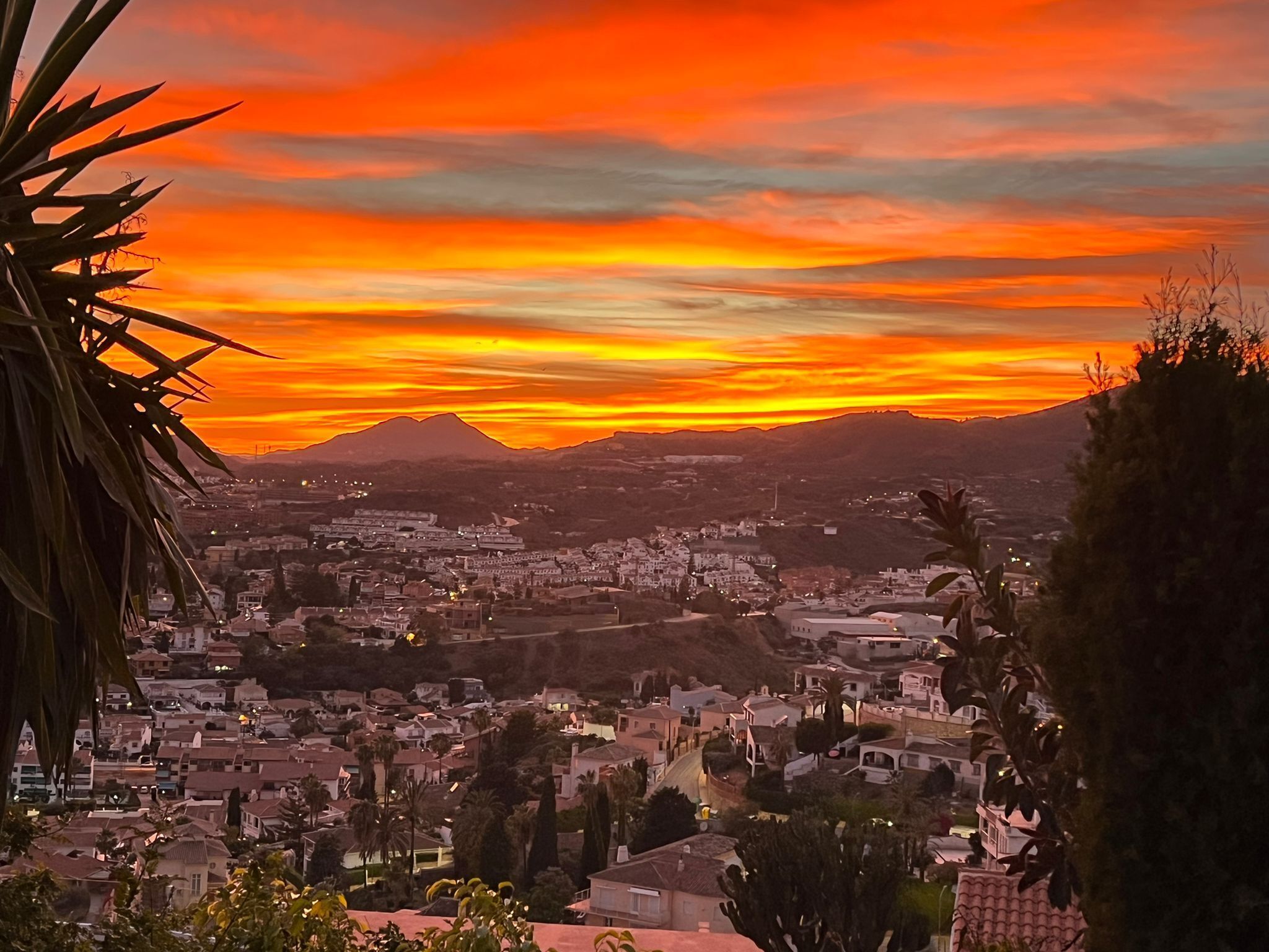 A town with a mountain in the background during sunset.