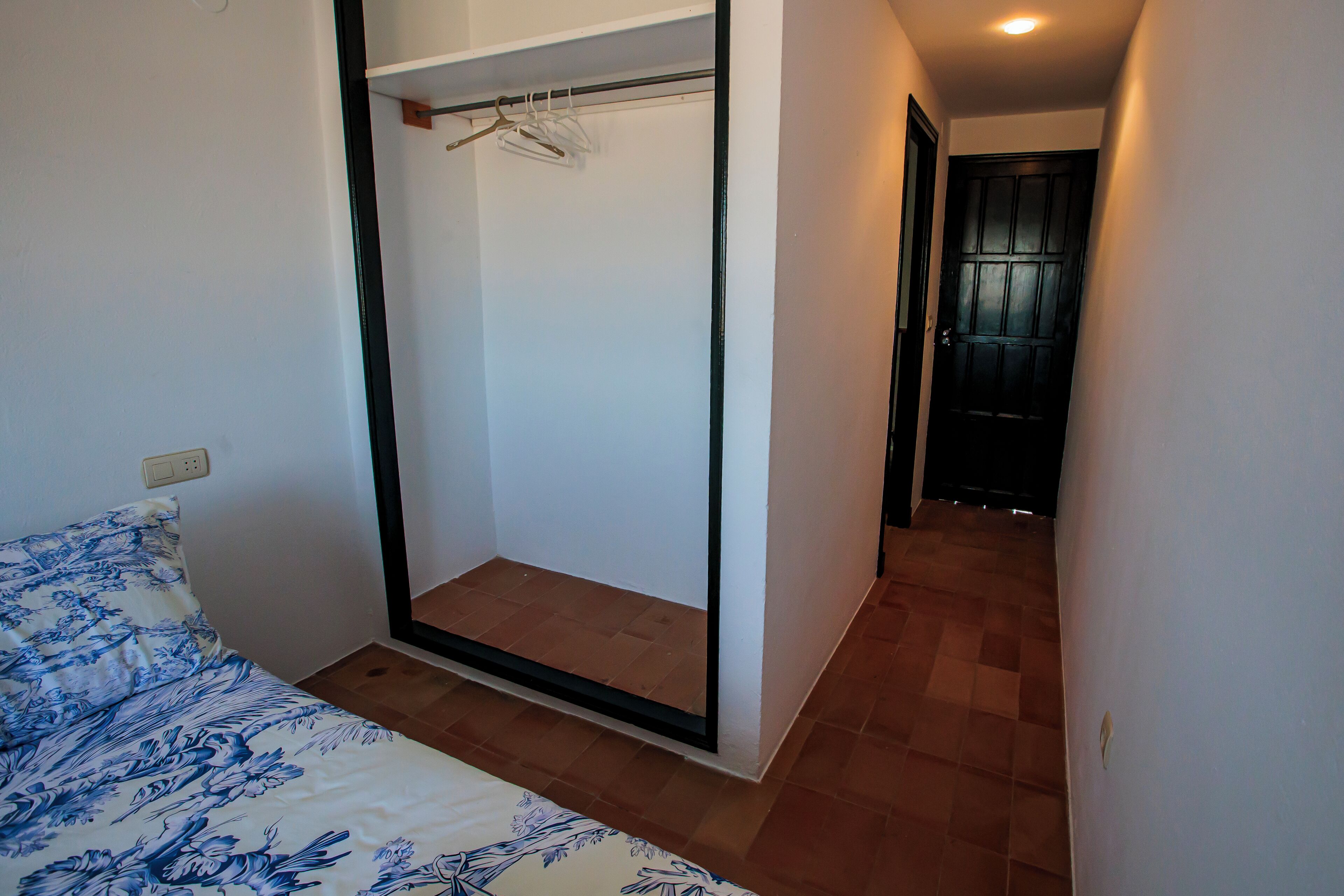 A bedroom with a bed, a wardrobe, and a door leading to another room.