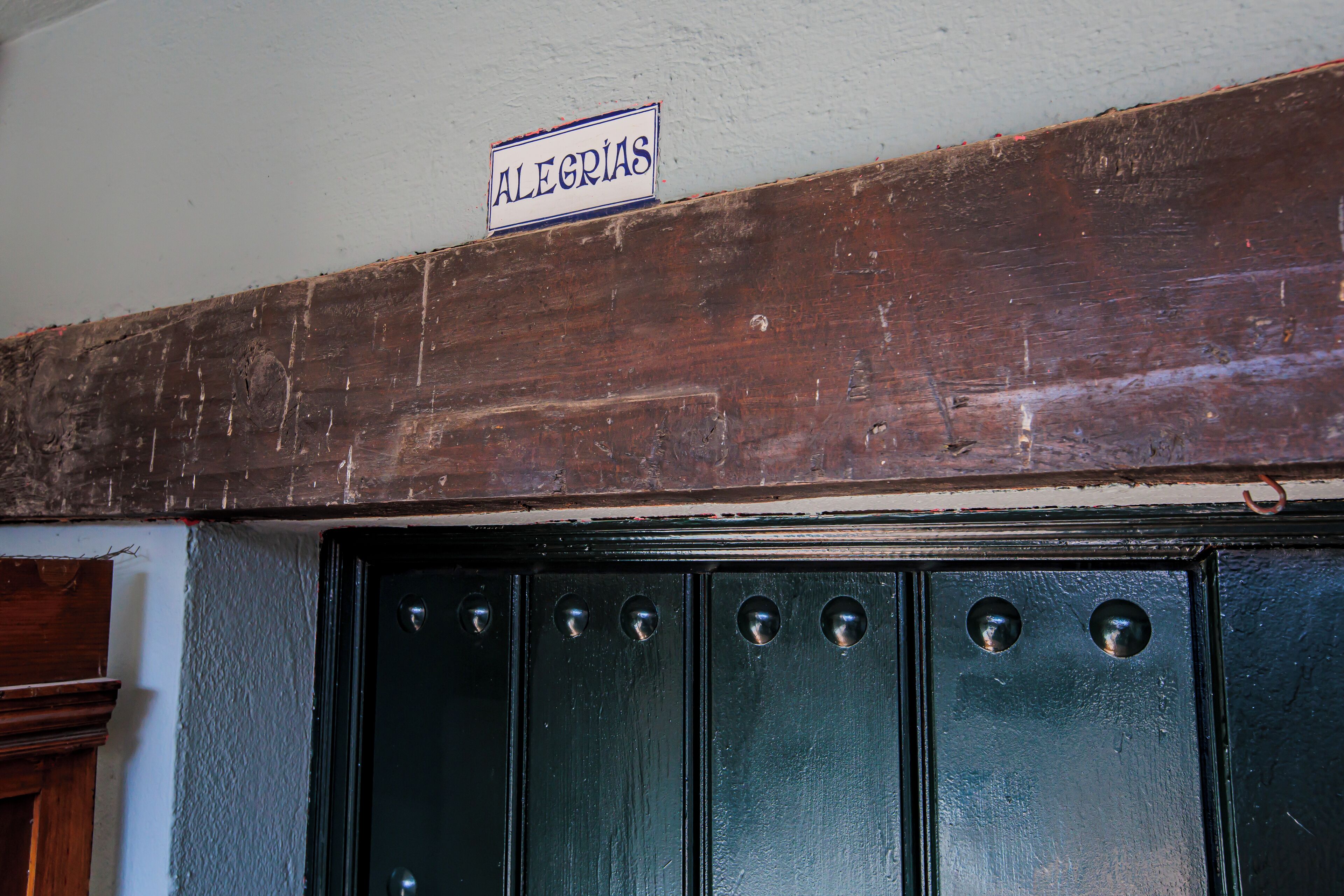 A wooden door with a sign above it that reads "ALEGRIAS."