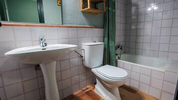 Un baño con lavamanos, inodoro y bañera blancos.