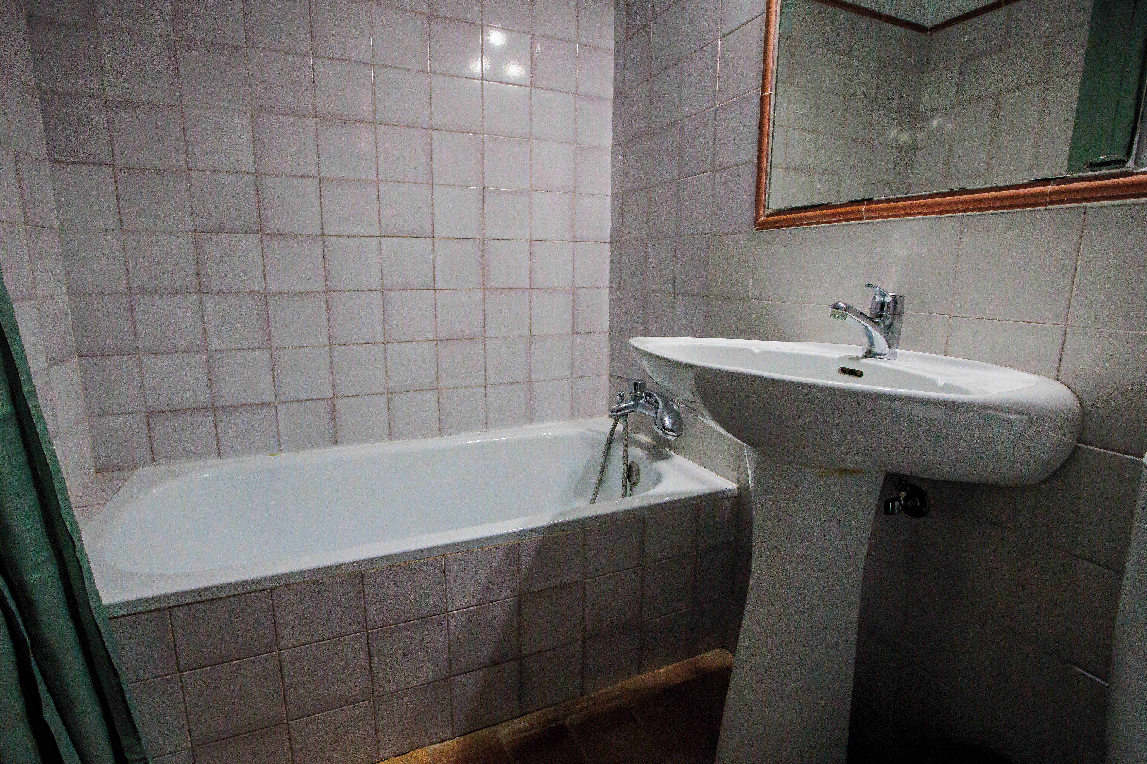 A bathroom with a bathtub, a sink, and a mirror.