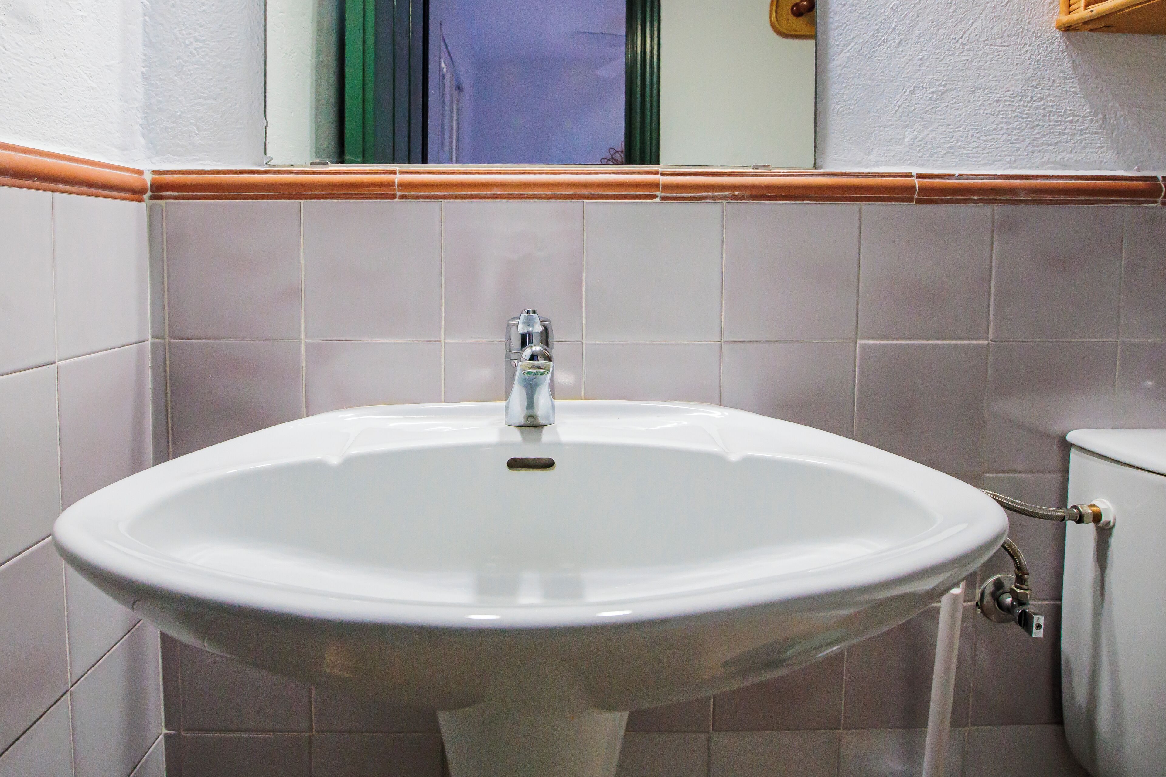 Een badkamer met een wit wastafel, een spiegel en een toilet.